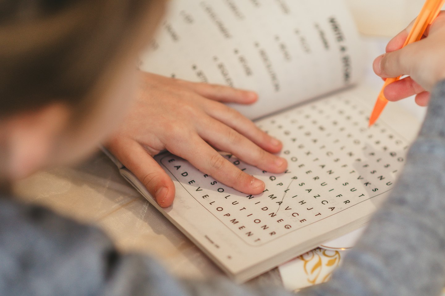 Hands marking the word 'LEADERSHIP' in a word search puzzle.